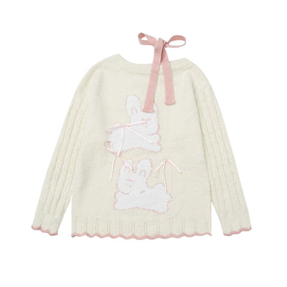 Light-colored sweater with bunny design and pink ribbon on a white background