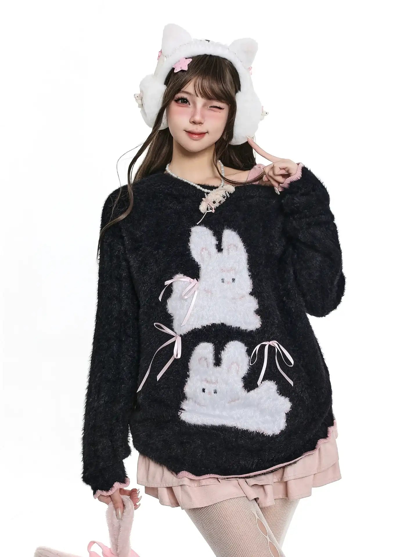 Person wearing a black sweater with bunny designs and cat ears on a white background