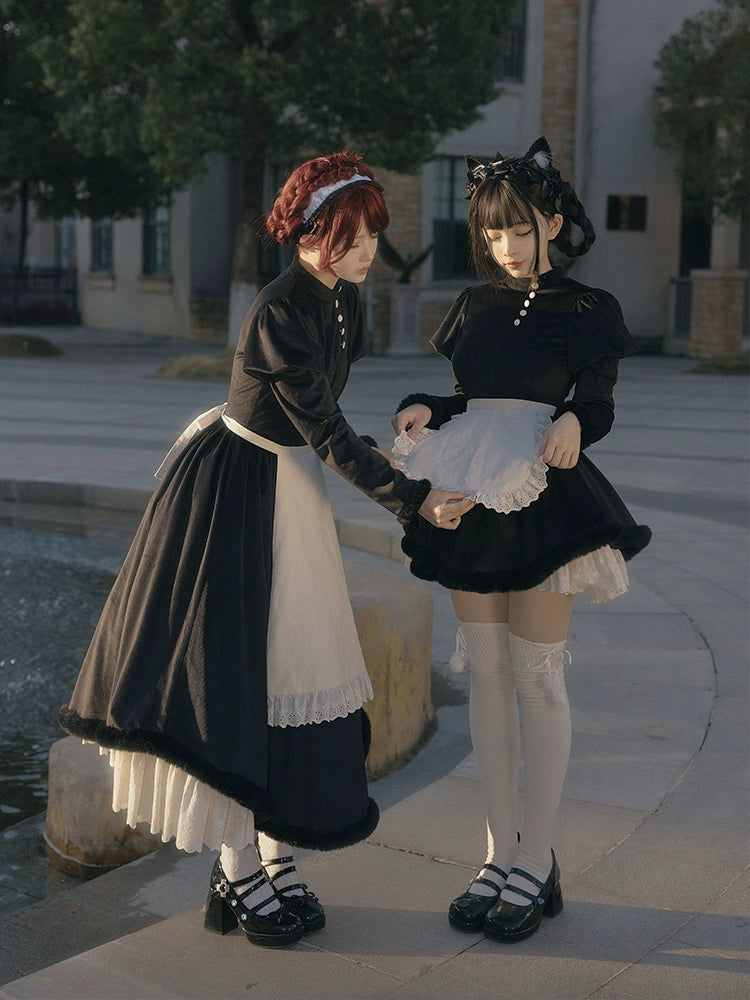 Two people in lolita maid outfits standing outdoors near a fountain.