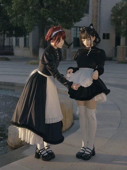 Two people in lolita maid outfits standing outdoors near a fountain.