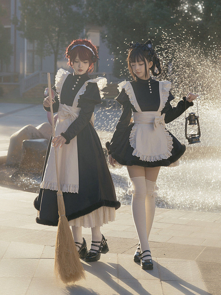 Two people in lolita maid costumes standing near a fountain.