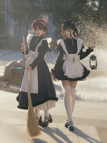 Two people in lolita maid costumes standing near a fountain.