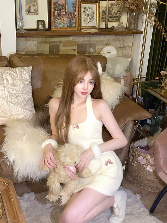 Woman in a white dress holding a teddy bear in a cozy living room.