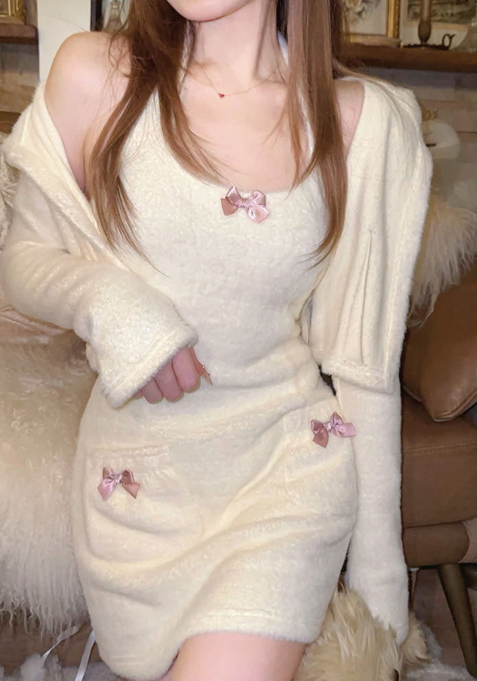 Person wearing a cream-colored dress with pink bow details indoors.