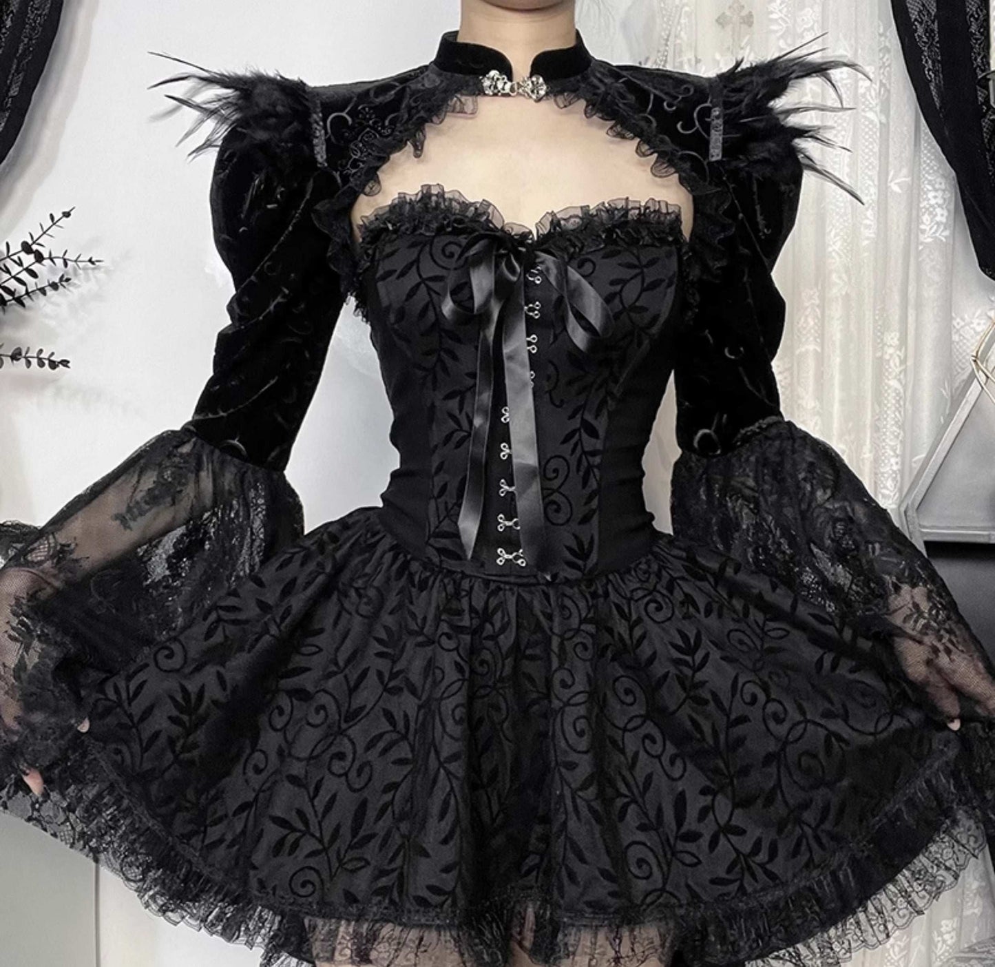 Black lace dress with intricate detailing on a neutral background