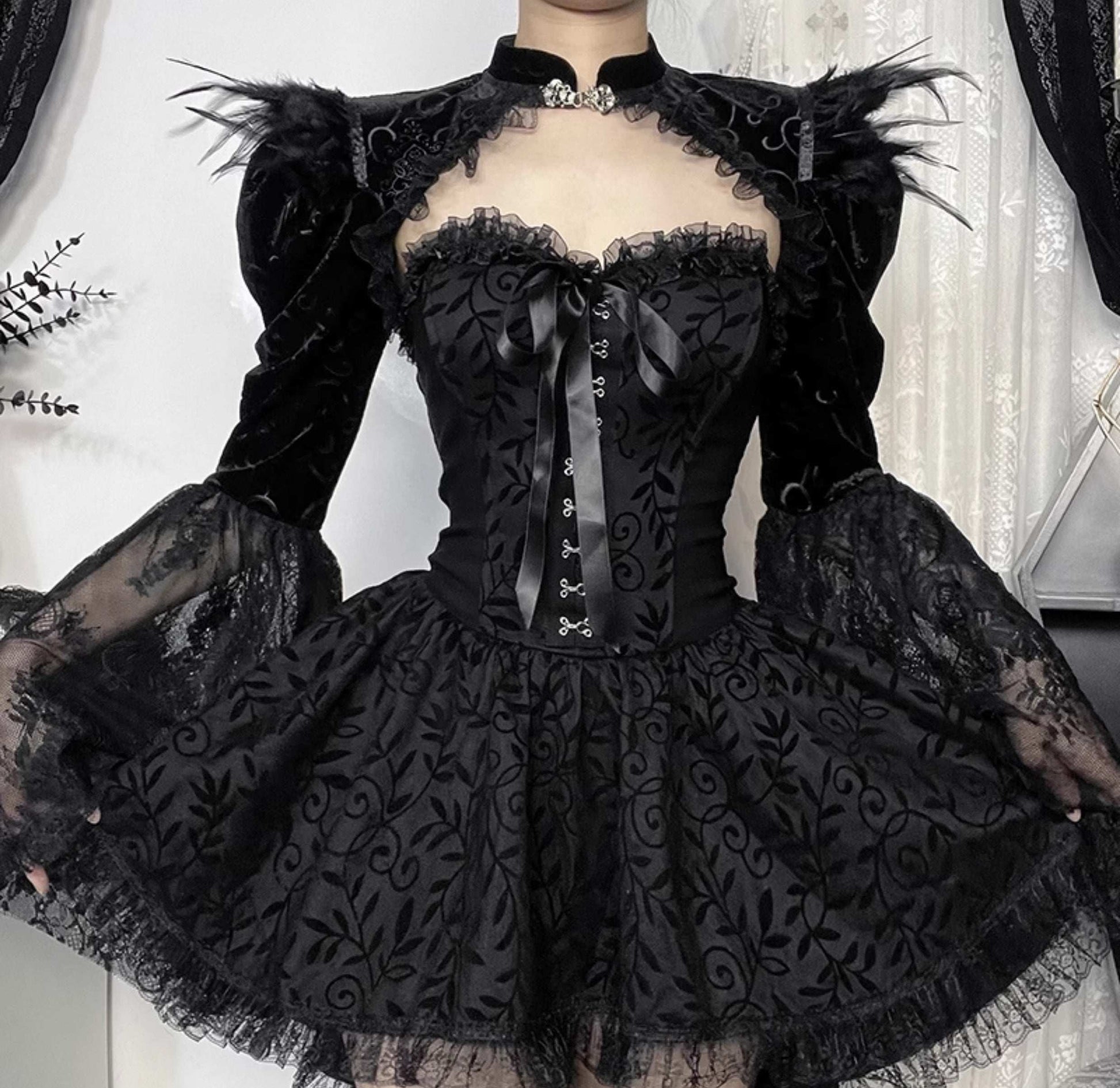 Black lace dress with intricate detailing on a neutral background