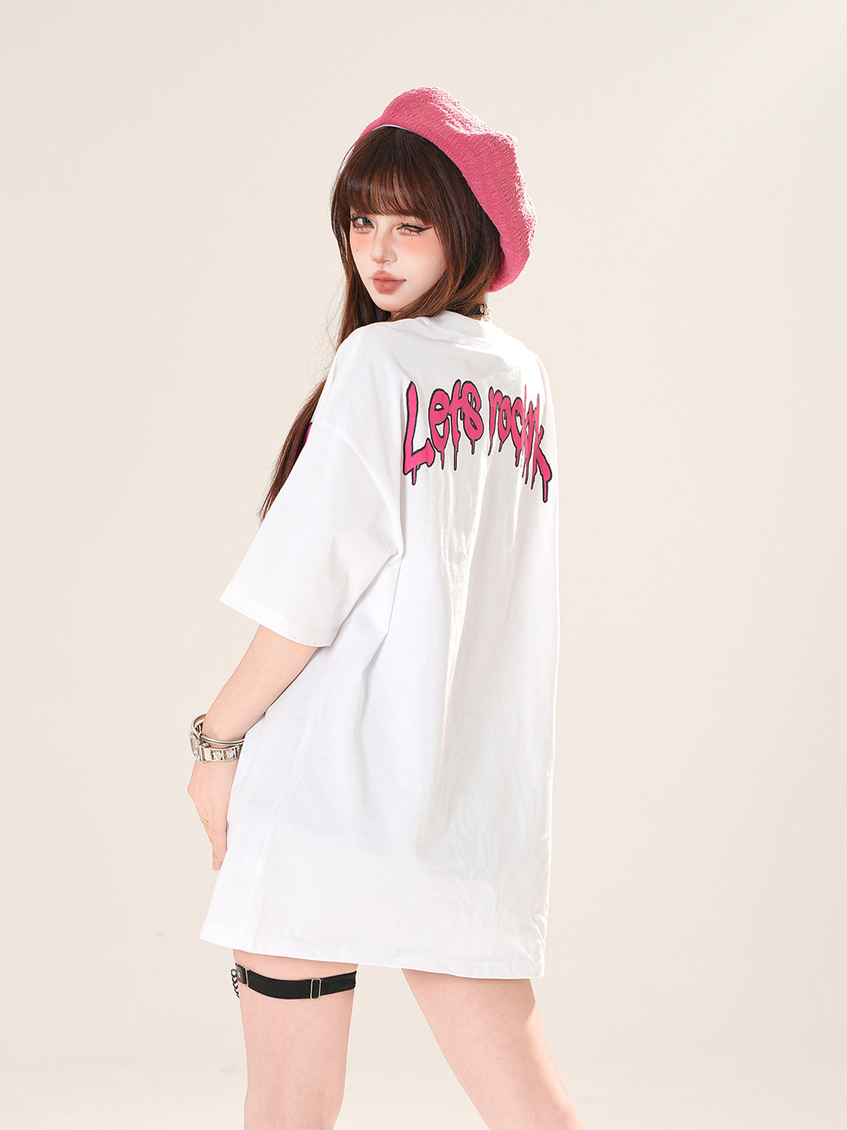 Person wearing a white shirt with pink text and a pink hat on a beige background