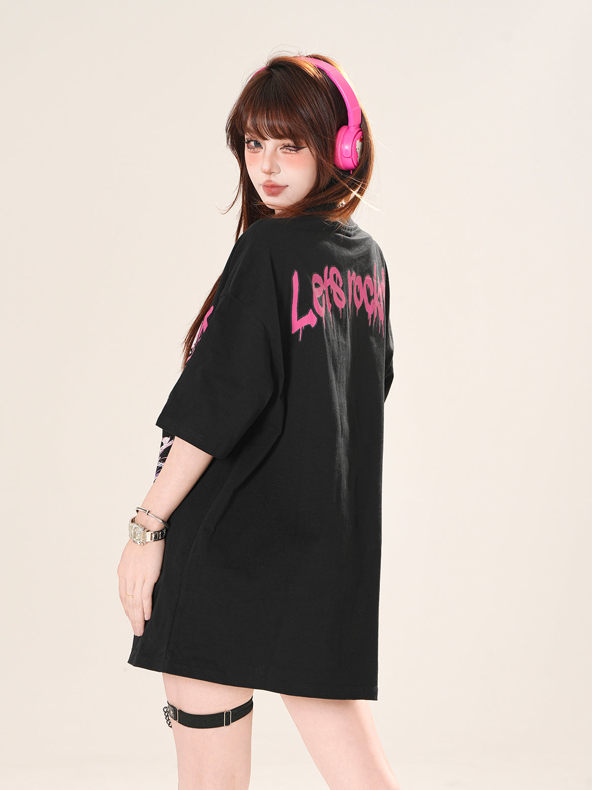 Person wearing a black oversized shirt with pink text, standing against a plain background