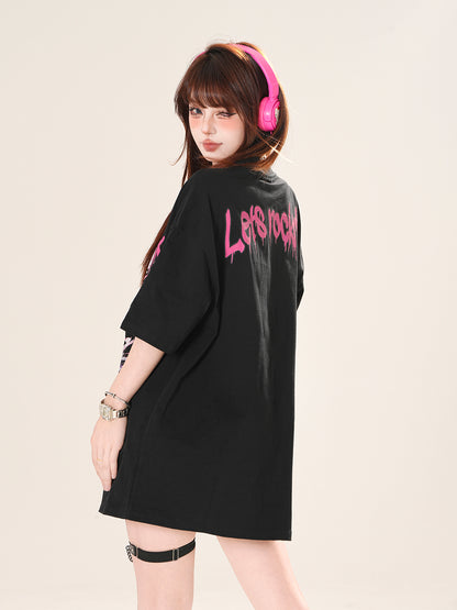 Person wearing a black oversized shirt with pink text, standing against a plain background