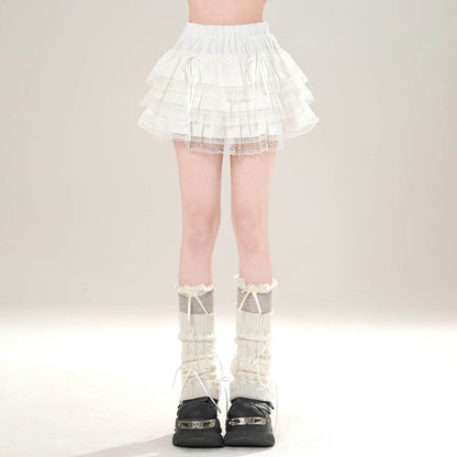 Person wearing a white lace skirt and black shoes on a plain background