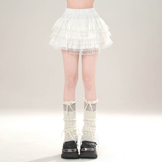 Person wearing a white lace skirt and black shoes on a plain background