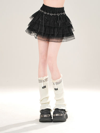 Person wearing a black tiered skirt, white knee-high socks, and black shoes on a light gray background