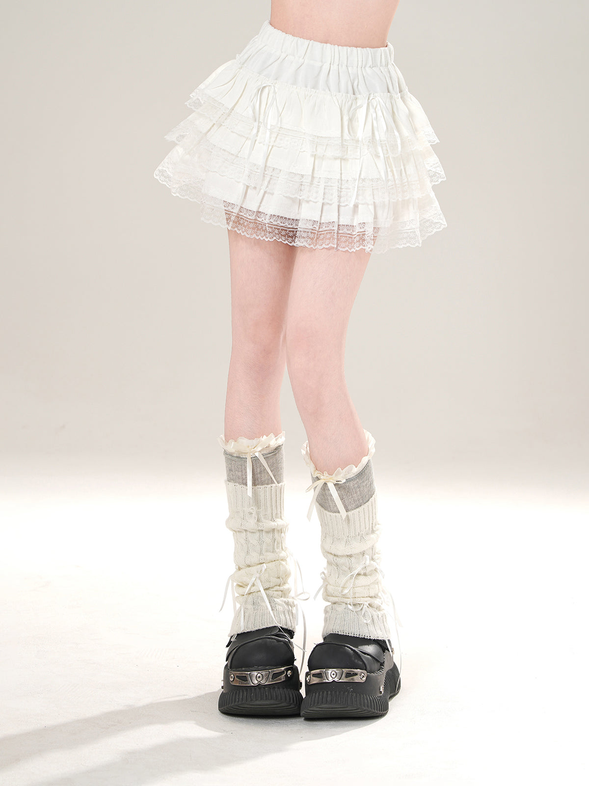 Person wearing a white skirt, sheer stockings, and black shoes on a plain background