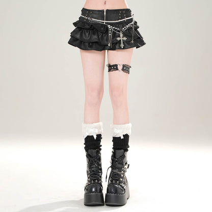 Person wearing a black mini skirt with decorative elements and black platform boots on a light gray background