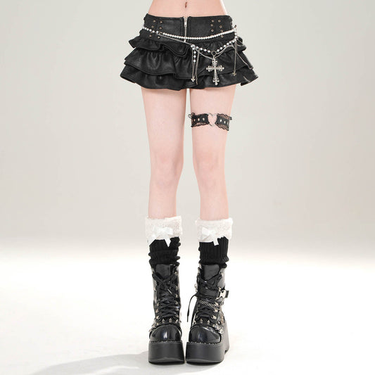 Person wearing a black mini skirt with decorative elements and black platform boots on a light gray background