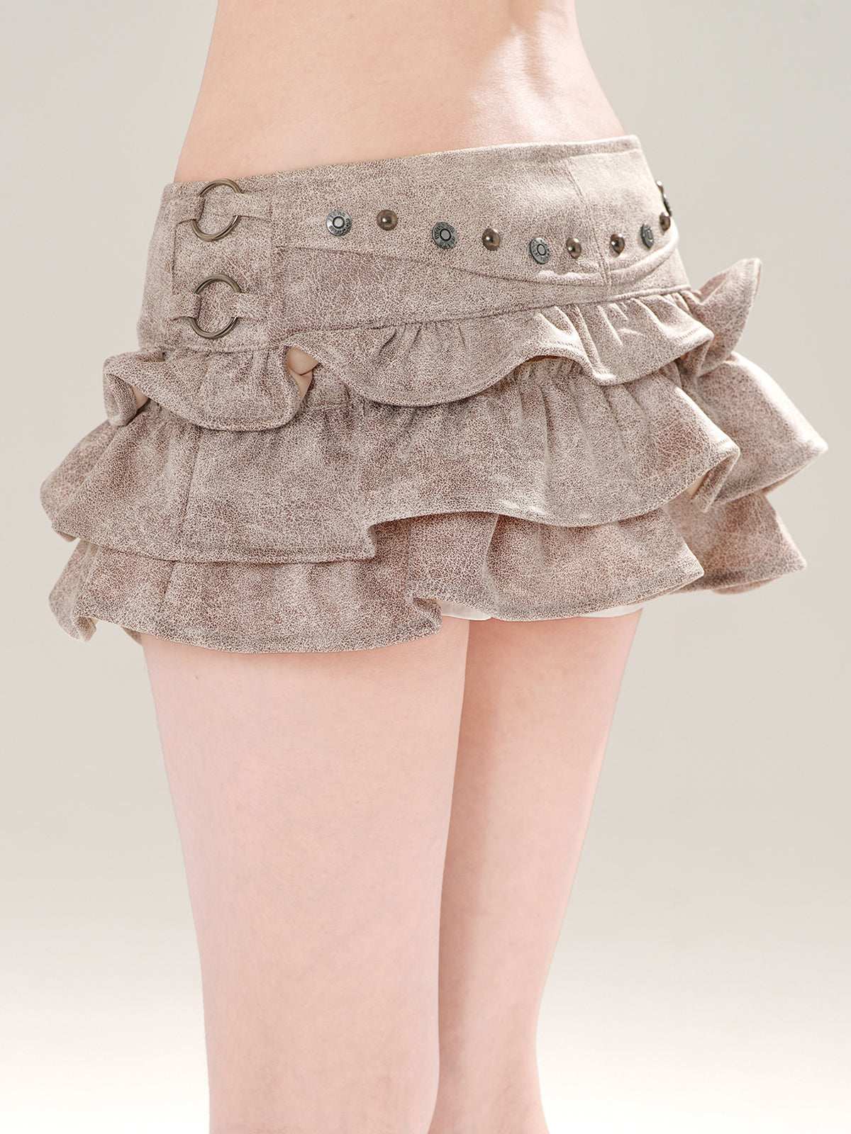 Brown ruffled skirt with decorative buttons on a neutral background