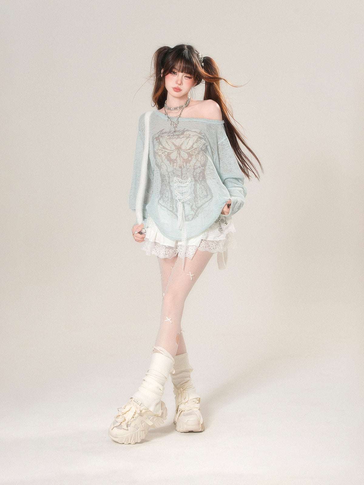 Person wearing a light blue off-shoulder top with lace details on a plain background