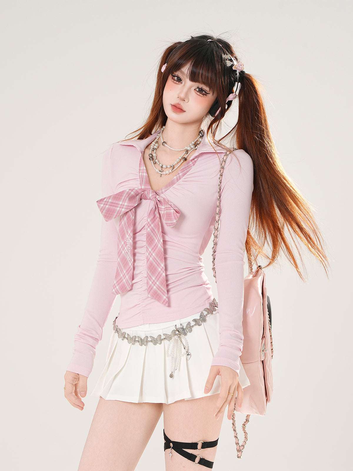 Woman wearing a pink outfit with a bow and white skirt on a plain background