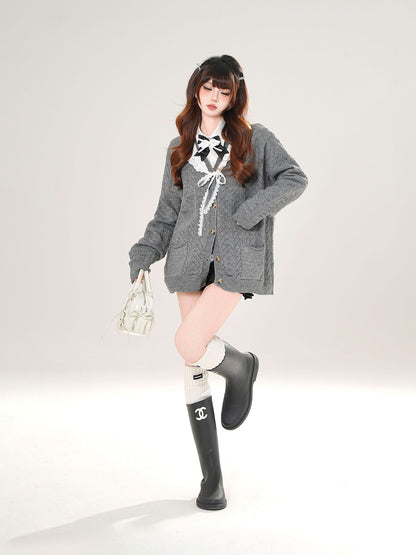 Woman wearing a gray cardigan, black skirt, white top with a bow, and black rain boots on a white background